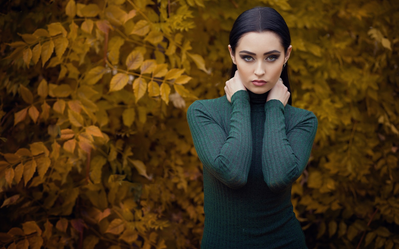 Красивая брюнетка позирует на фоне желтых листьев