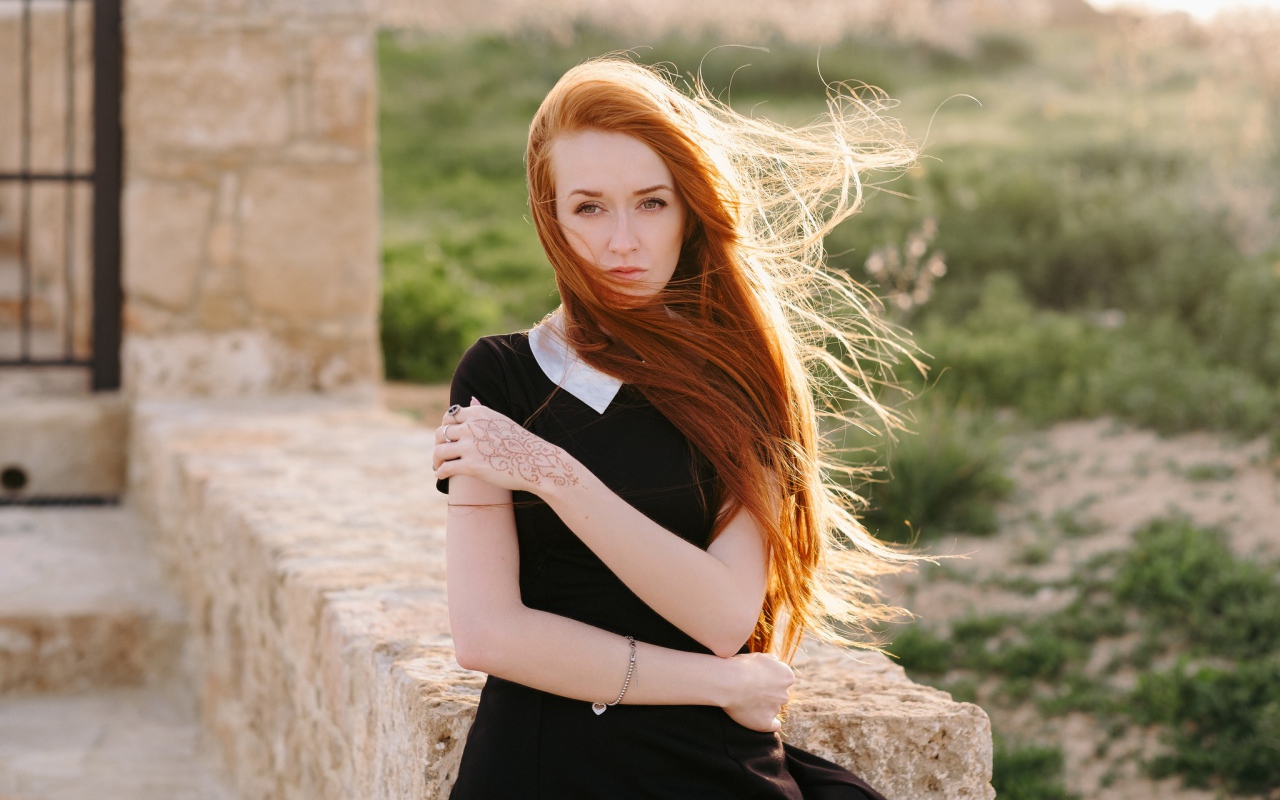 Красивая рыжеволосая девушка в черном платье с рисунком на руке