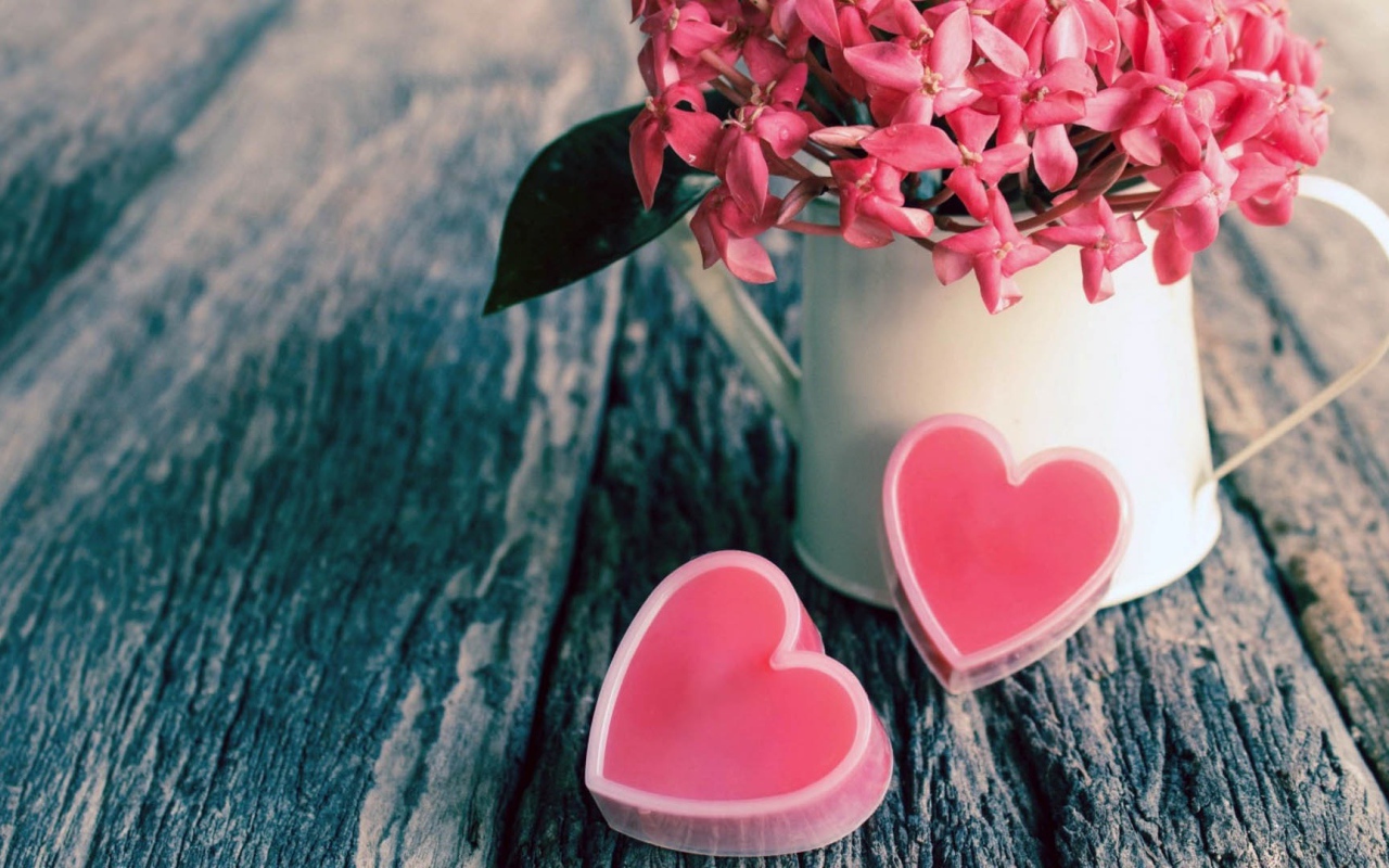 Розовые цветы в белой вазе и два розовых сердца 