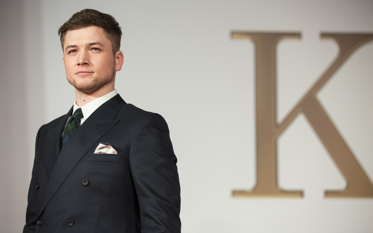 Молодой актер Терон Эгертон в черном пиджаке