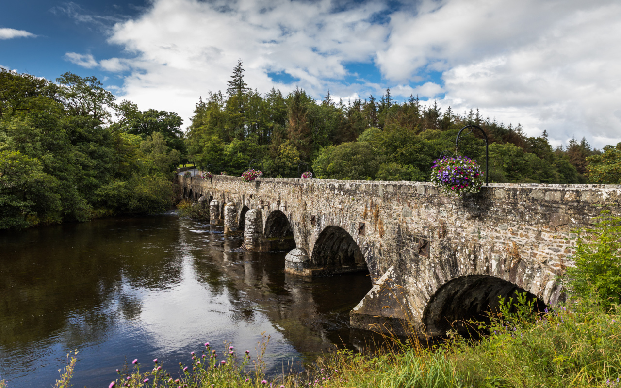 Мост через реку у леса на фоне красивого голубого неба с белыми облаками. Ирландия