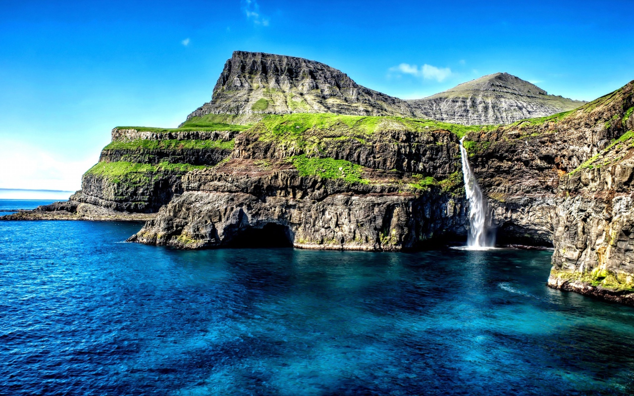 Маленький водопад стекает со скалы в океан, Гавайские острова