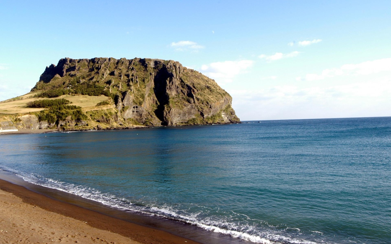 Гора на фоне спокойной воды моря под голубым небом