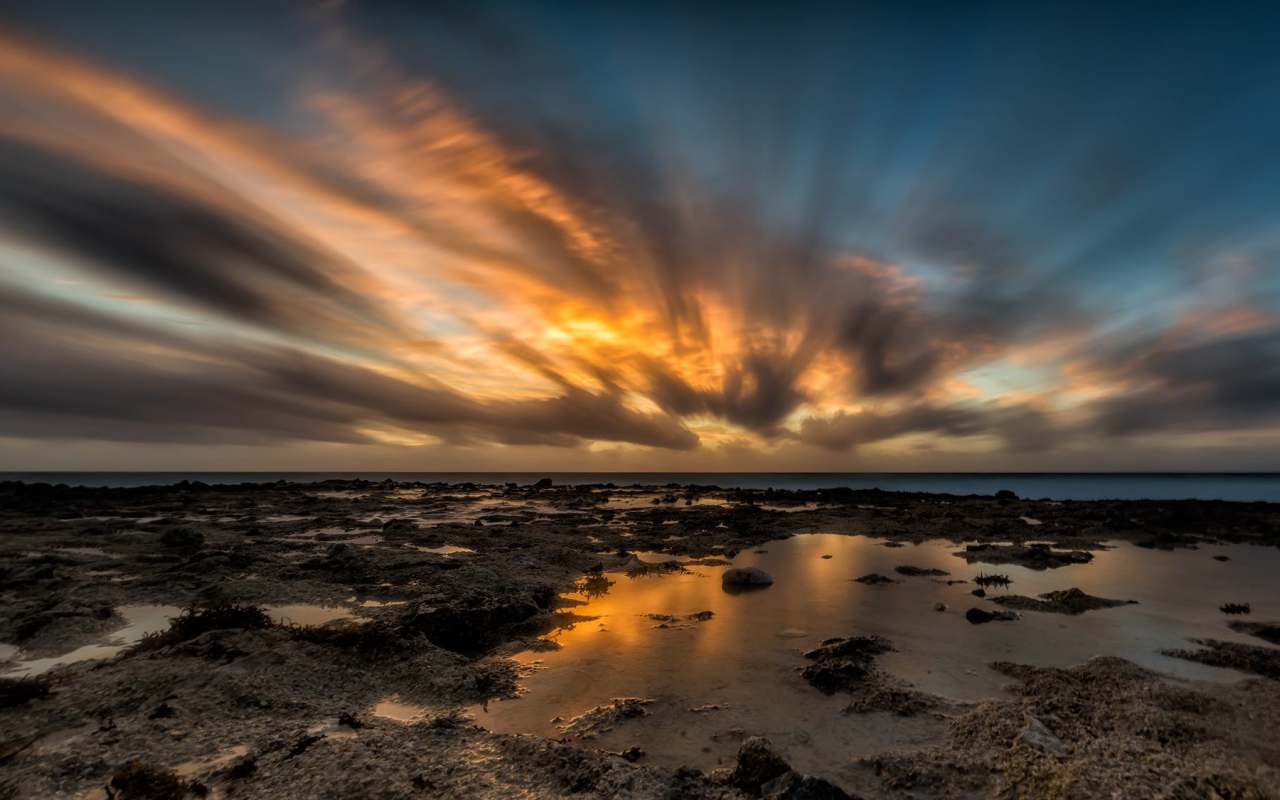 Закат солнца в облаках над водой 