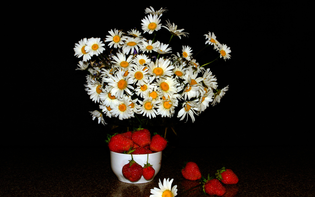 Белые полевые ромашки и клубника на столе на черном фоне