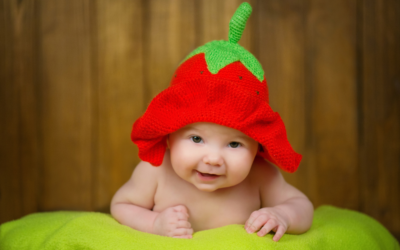 Младенец в забавной шапке клубнике на голове