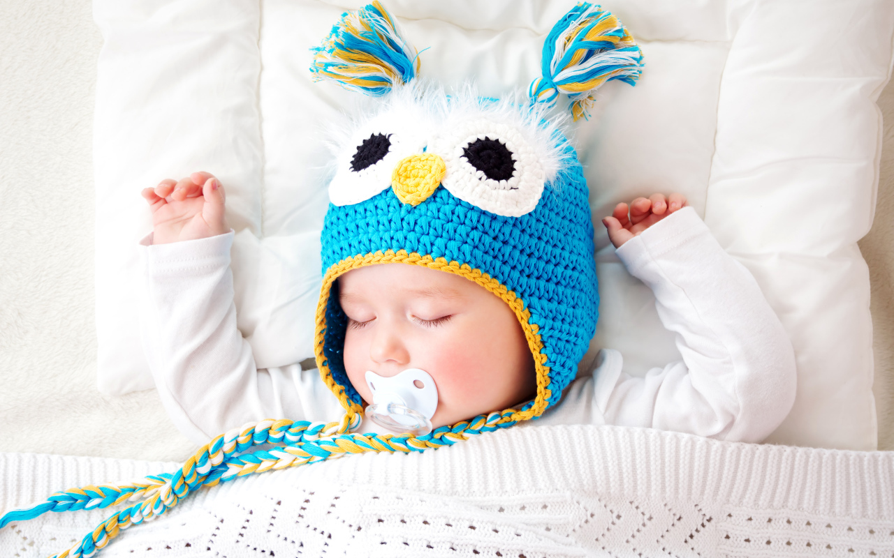 Спящий ребенок в забавной вязаной шапке