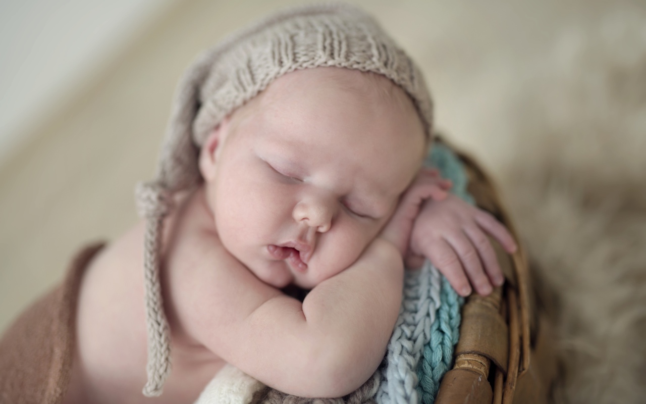 Маленький грудной ребенок спит в вязаной шапке