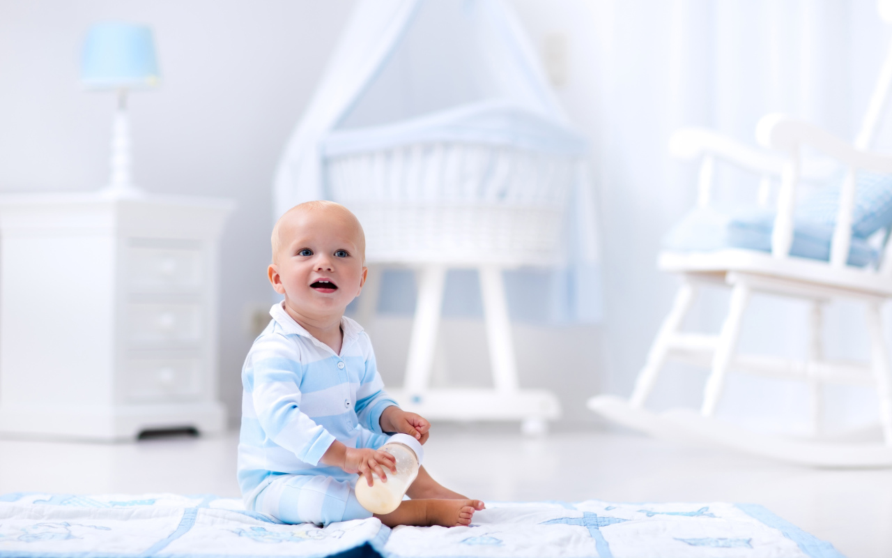 Маленький голубоглазый мальчик сидит на полу в комнате