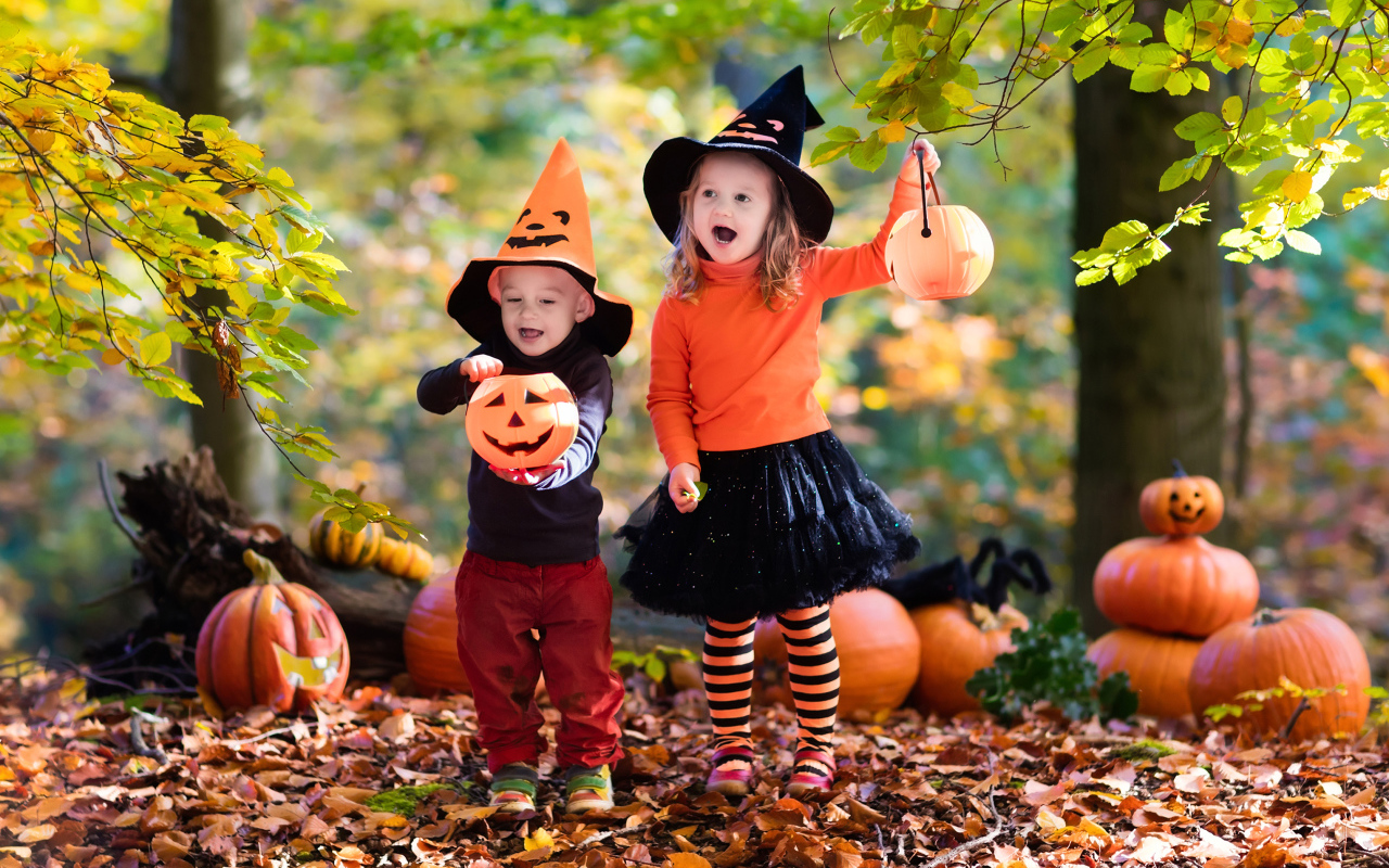 Маленькие мальчик и девочка в костюмах с тыквами на Хэллоуин