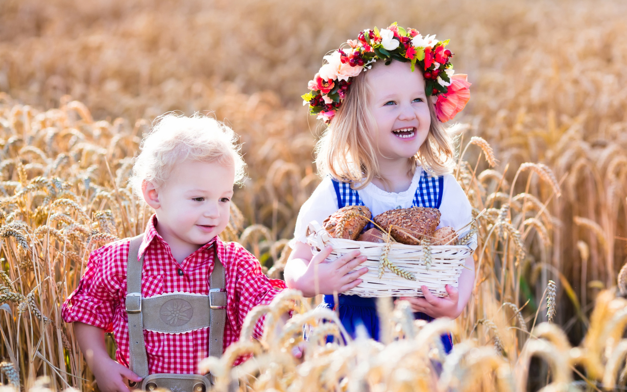 Маленькие мальчик и девочка на поле пшеницы с корзиной свежей выпечки