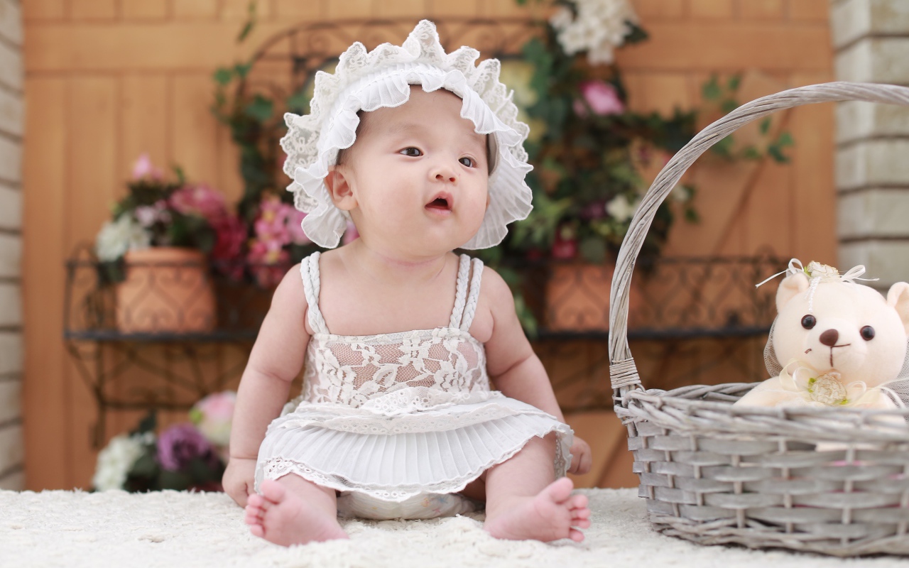 Маленькая девочка в белом платье с медвежонком в корзине