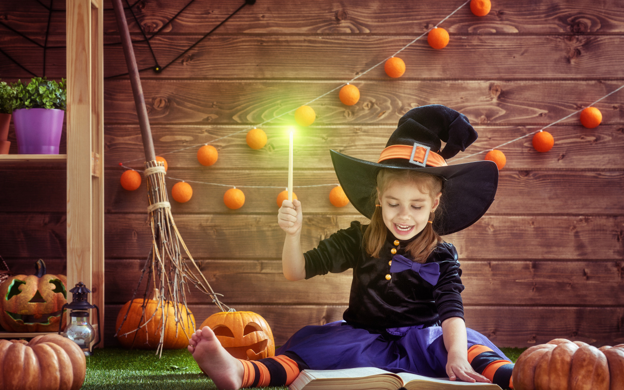 Маленькая девочка в костюме ведьмы с волшебной книгой на Хэллоуин