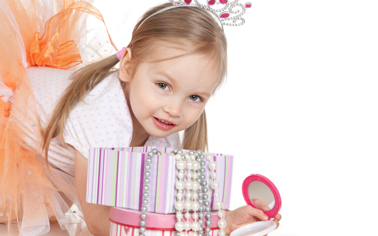 Маленькая девочка в короне на голове и с зеркалом на белом фоне