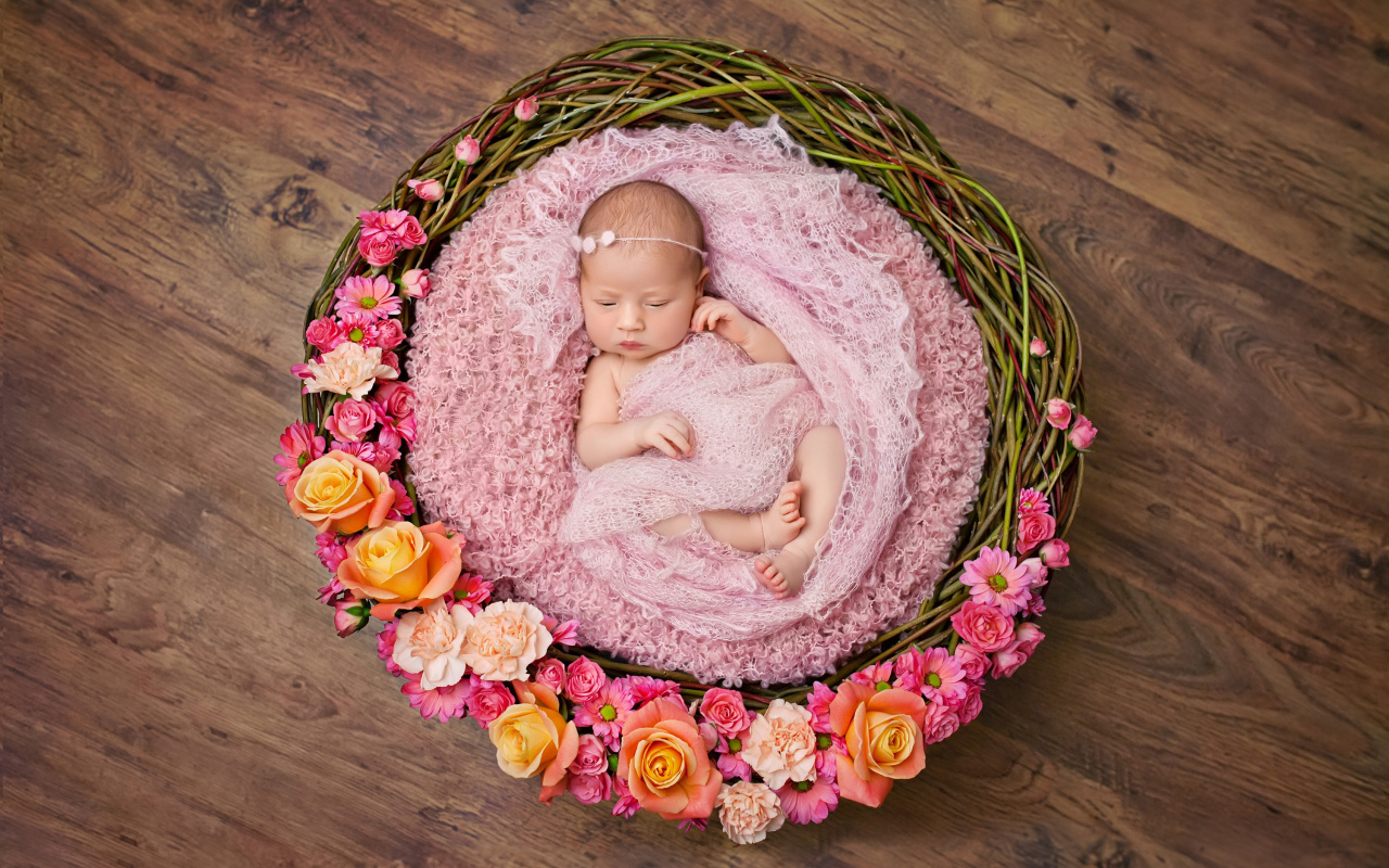 Маленькая девочка спит в корзине украшенной цветами