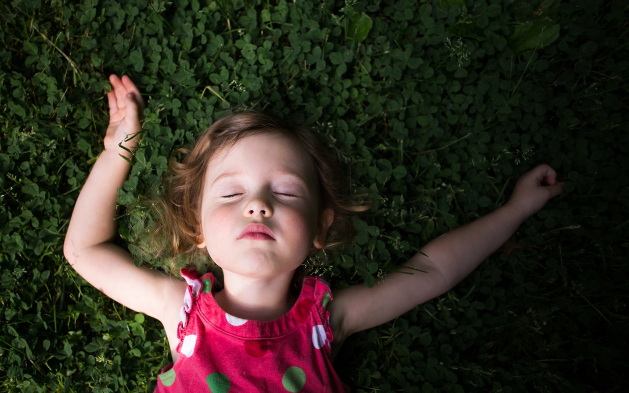 Маленькая девочка спит на зеленой траве 