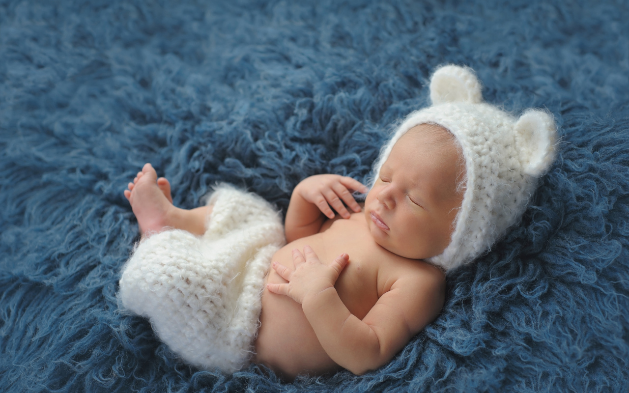 Спящий грудной ребенок в белом костюме медвежонка