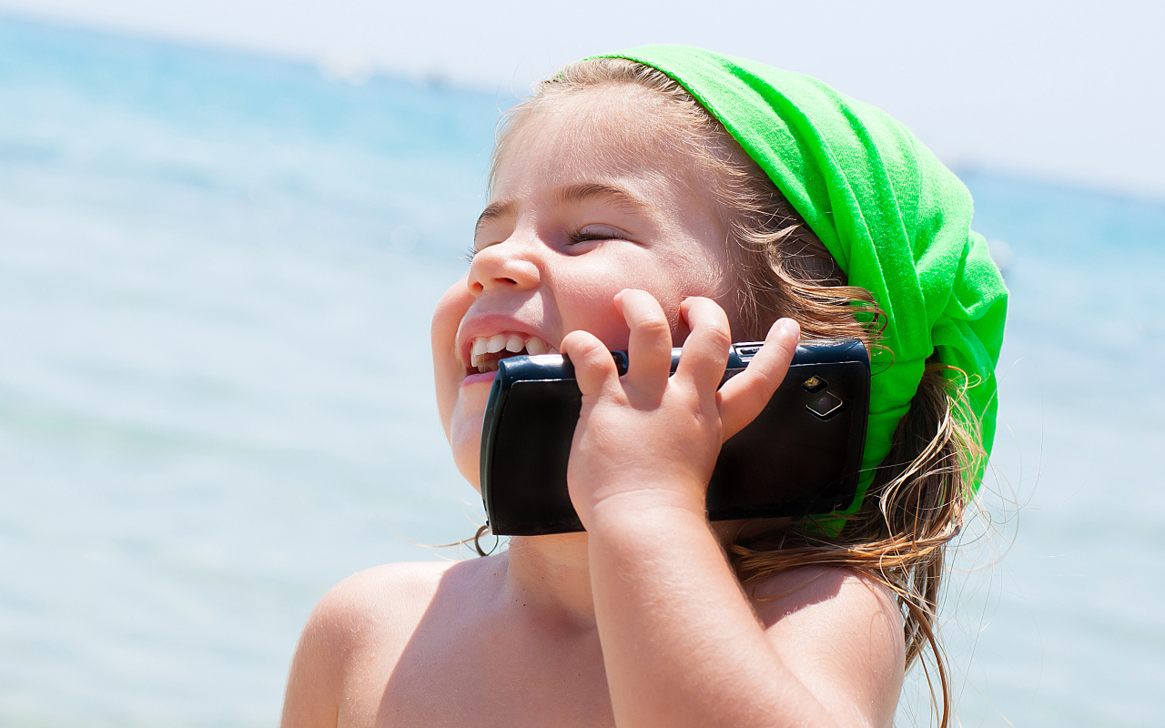 Улыбающаяся девочка в зеленом платке разговаривает по телефону