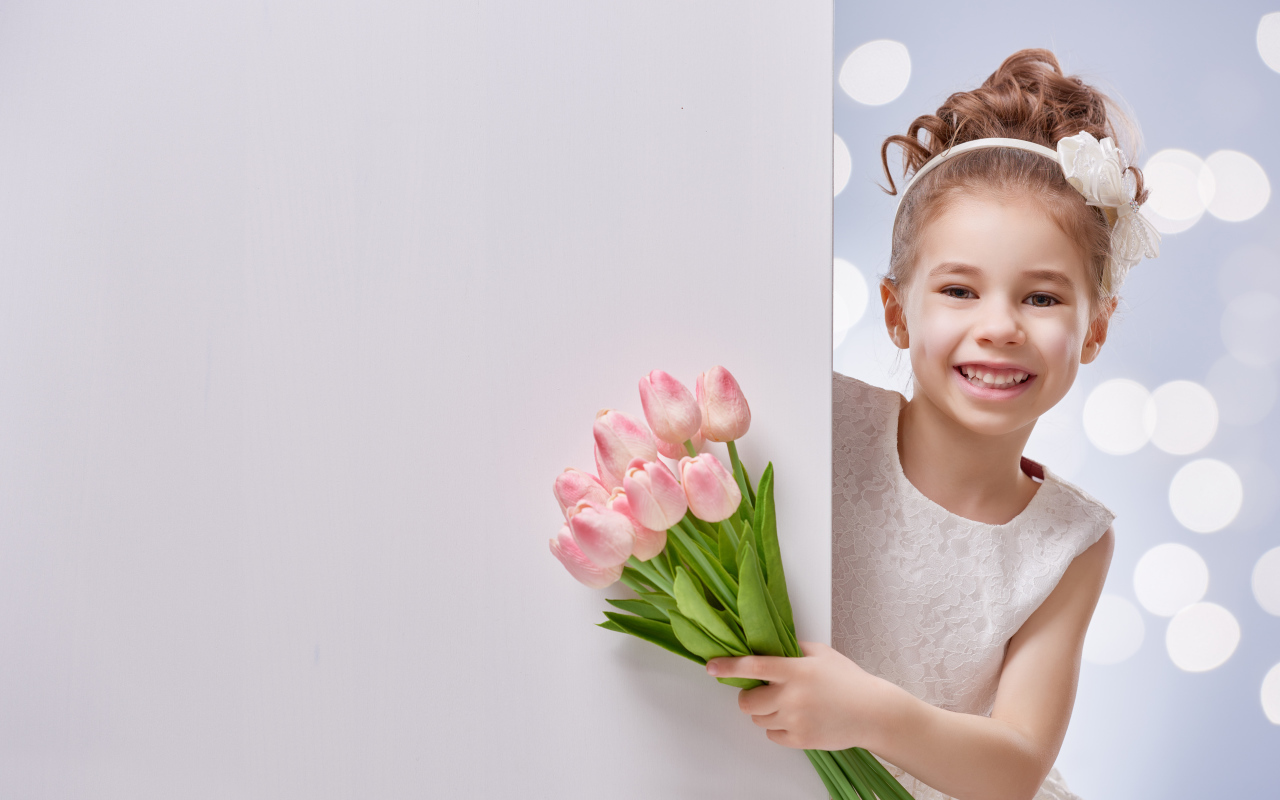 Улыбающаяся маленькая девочка с букетом розовых тюльпанов