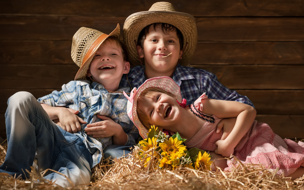 Два улыбающихся мальчика и девочка в соломенных  шляпах