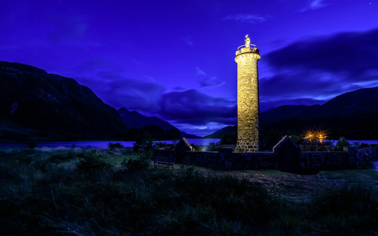 Ночной маяк у побережья на фоне гор, деревня Гленфиннан. Шотландия