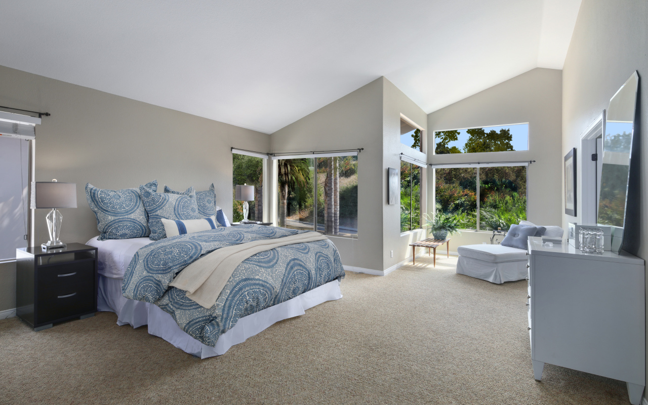 Уютная спальная комната в серых тонах с большими окнами