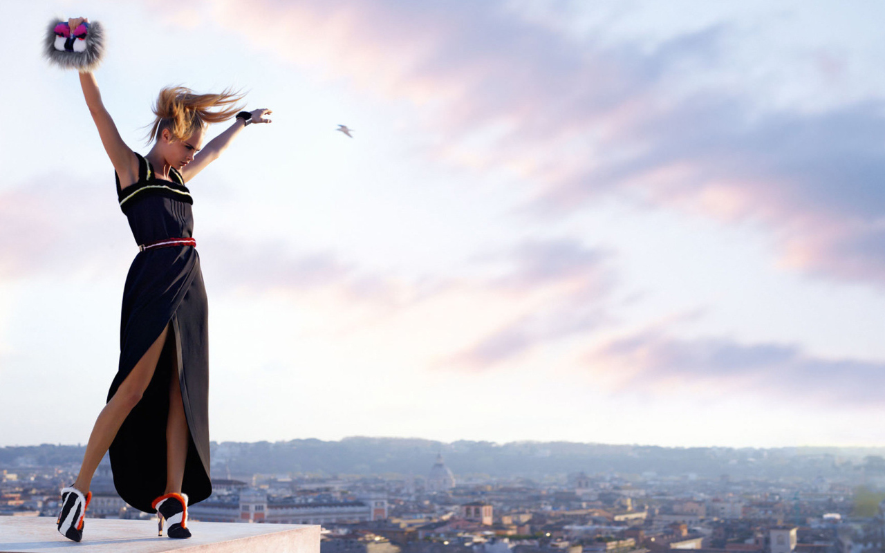 Актриса Кара Делевинь в черном платье на фоне неба 