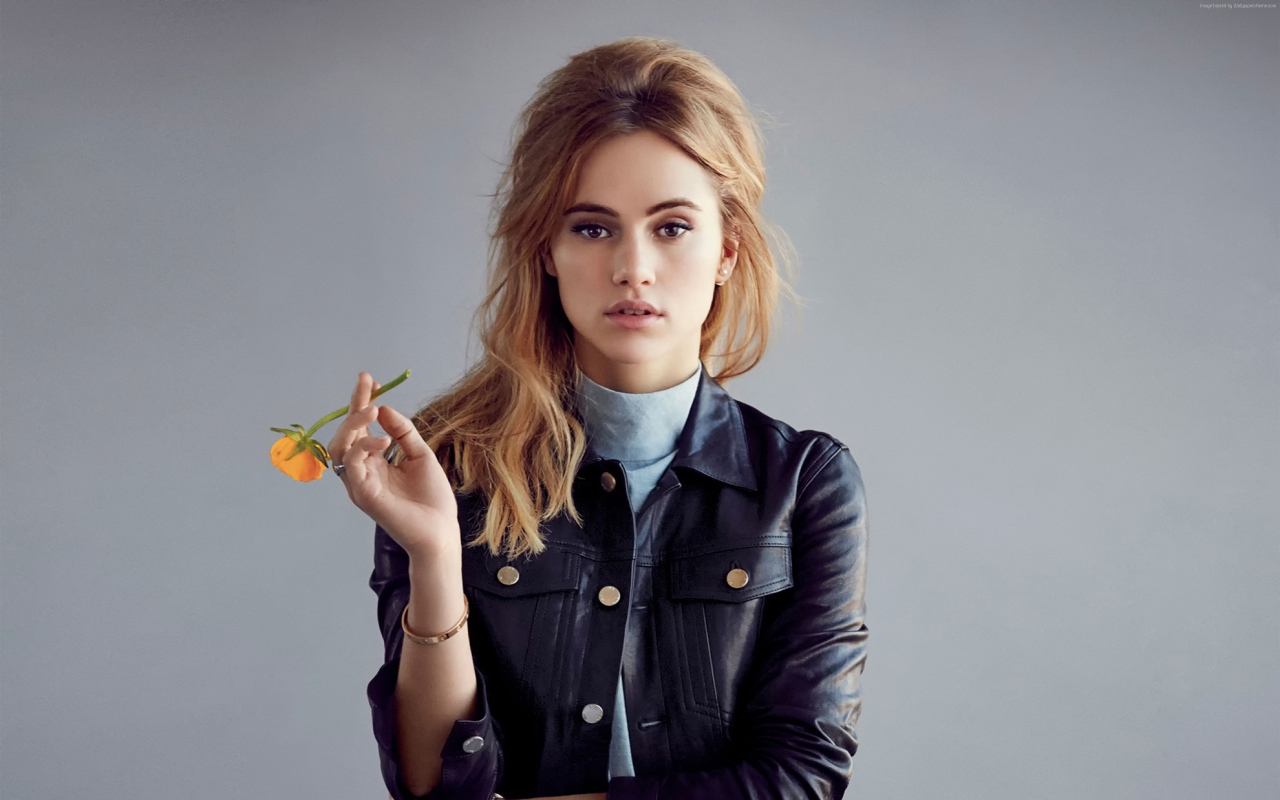 Актриса Сьюки Уотерхаус с цветком в руках на сером фоне