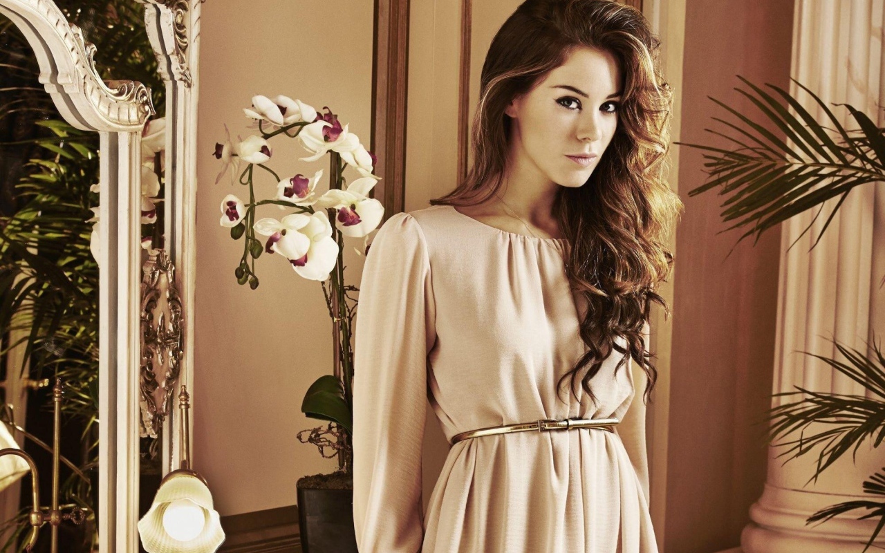 Брюнетка актриса Роксанна Макки стоит рядом с цветком орхидеи