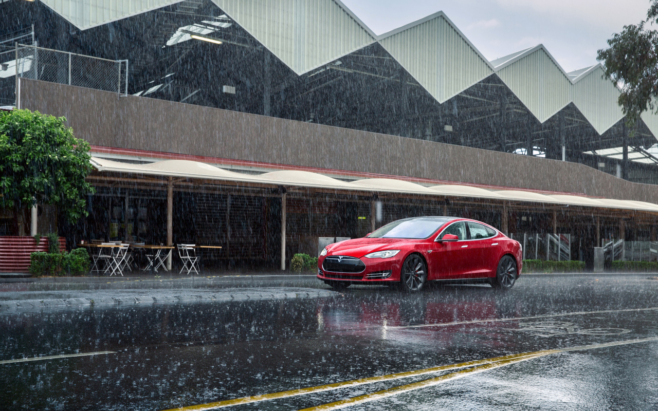 Красный автомобиль  Tesla Model S на дороге под дождем