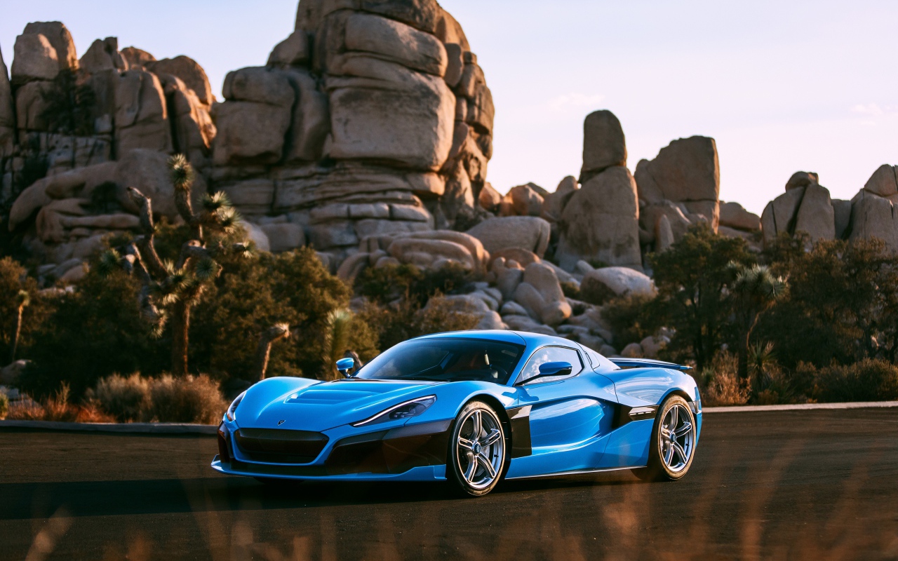 Голубой спортивный автомобиль  Rimac C_Two на фоне гор