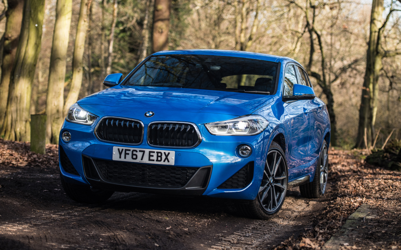 Синий автомобиль BMW X2 xDrive20d M Sport, 2018 на дороге в лесу