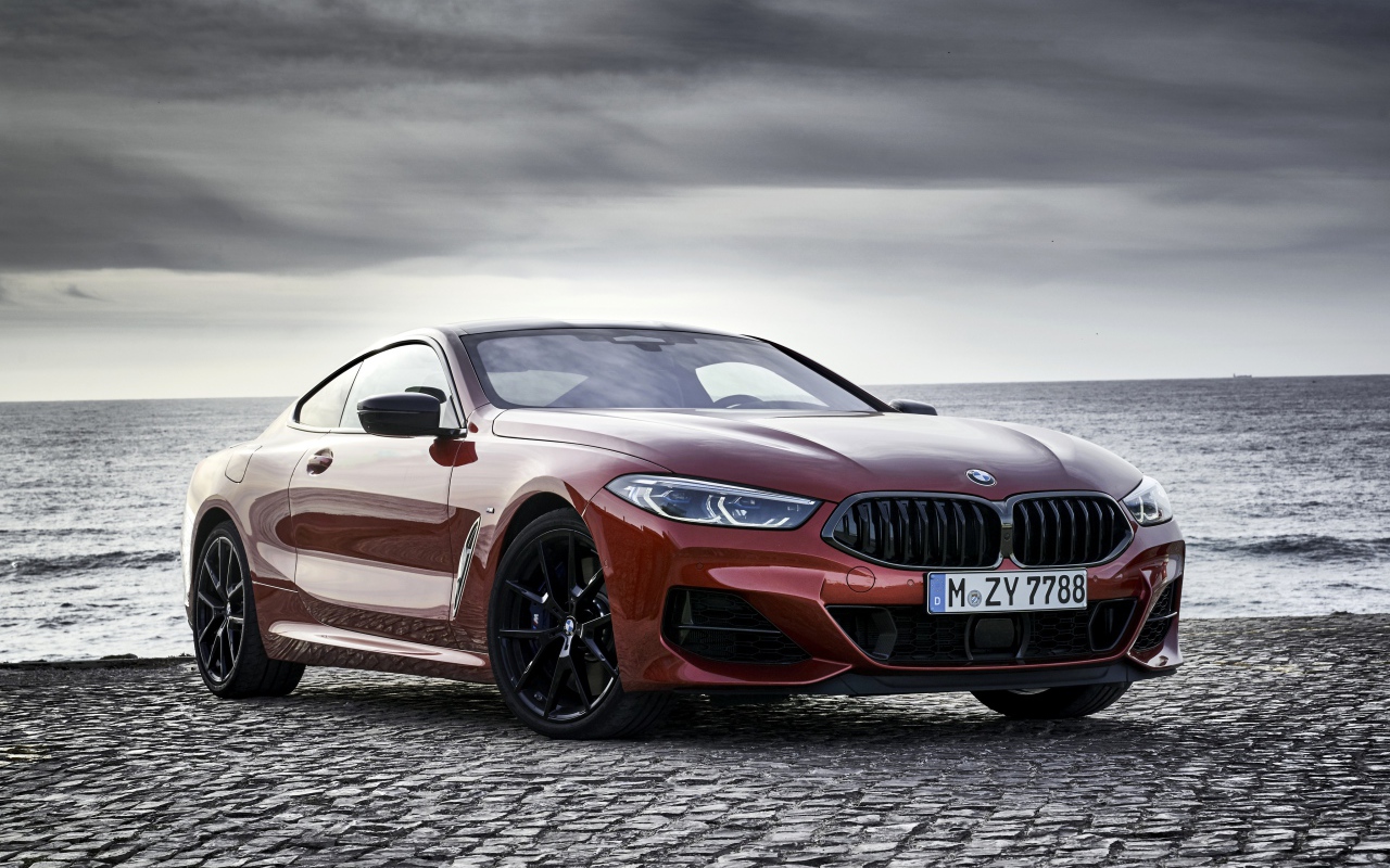 Красный автомобиль BMW 8 Series на фоне моря