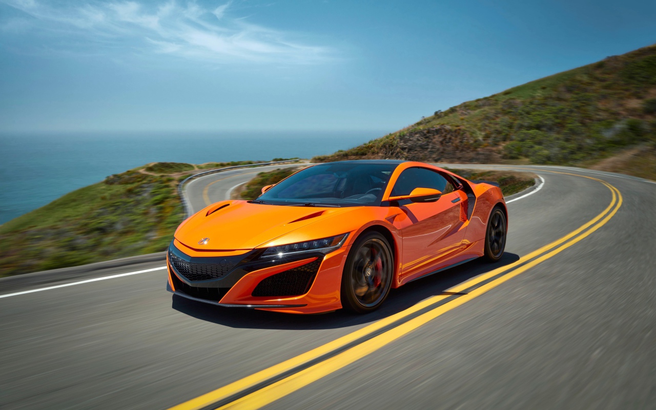 Оранжевый автомобиль Honda NSX на трассе под голубым небом