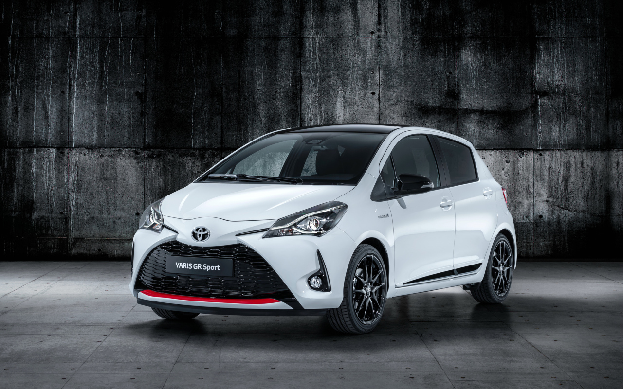 Белый автомобиль Toyota Yaris на сером фоне 