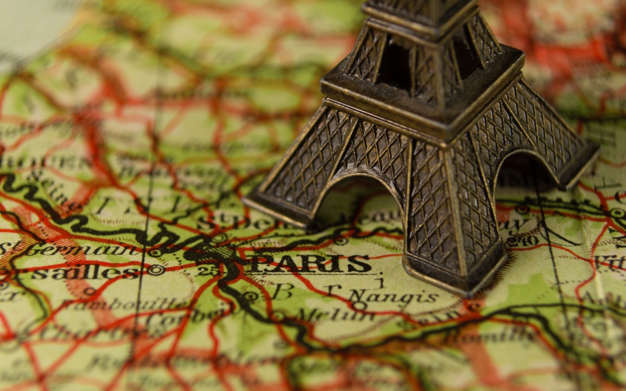 Маленькая статуэтка Эйфелева башня стоит на карте