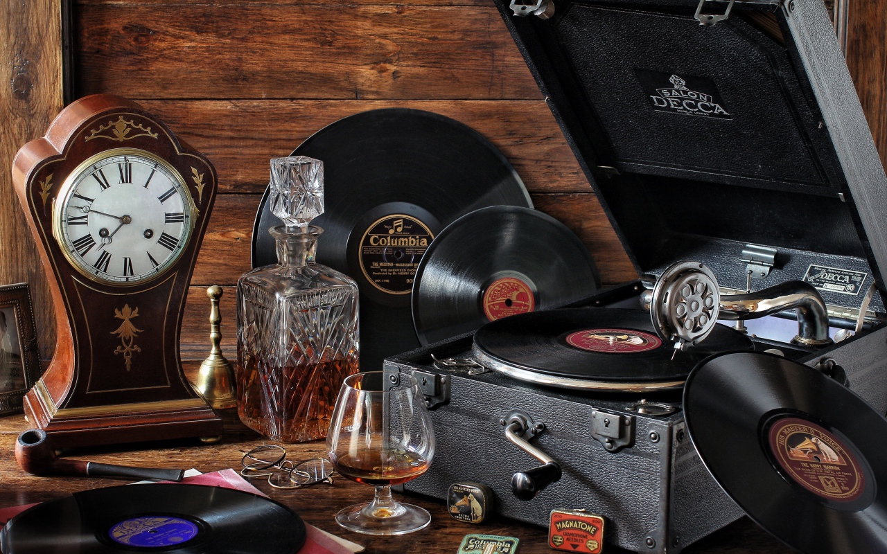 Старый граммофон с виниловыми пластинками, часами и коньяком на столе
