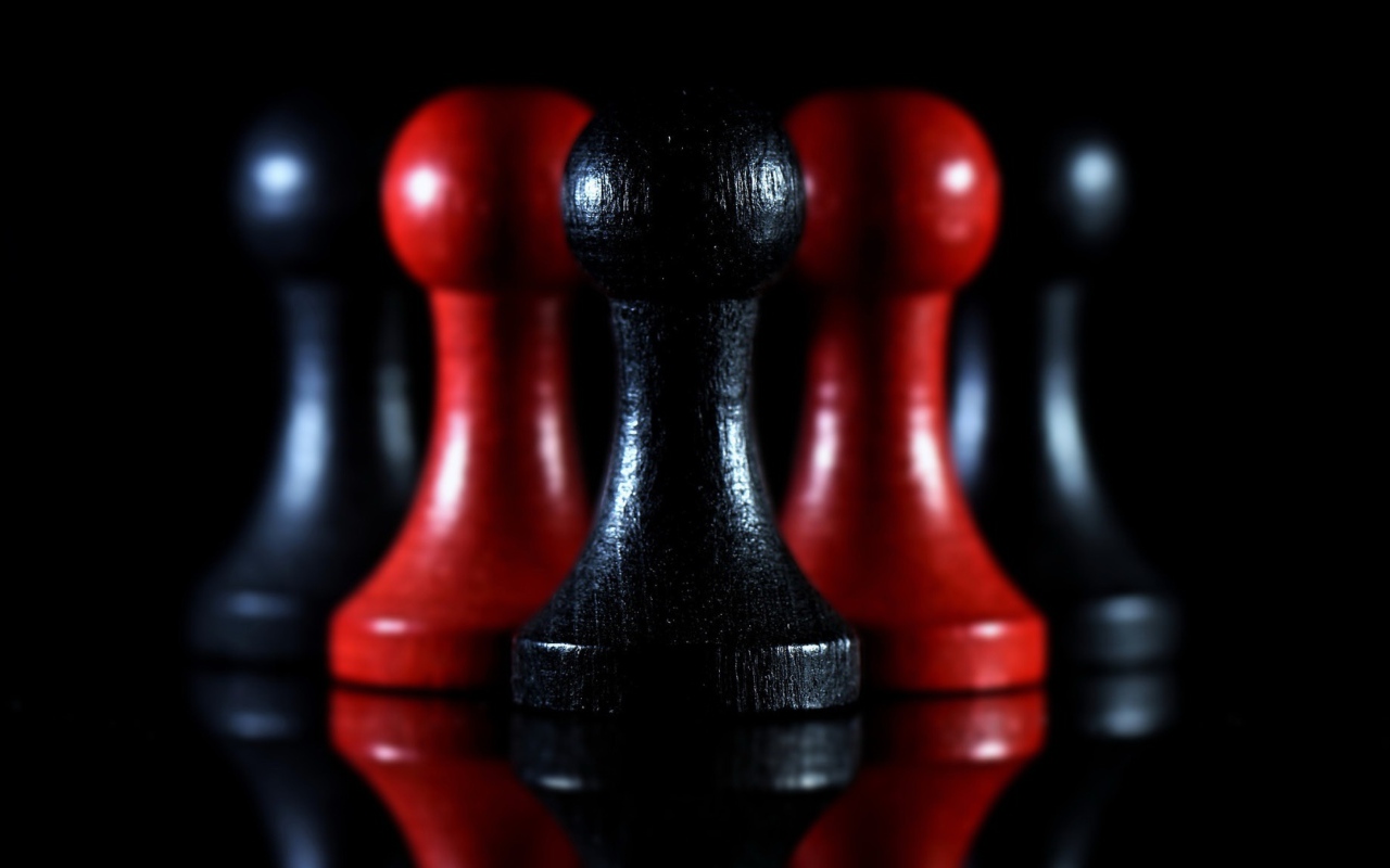 Красные и черные шахматные фигуры на черном фоне