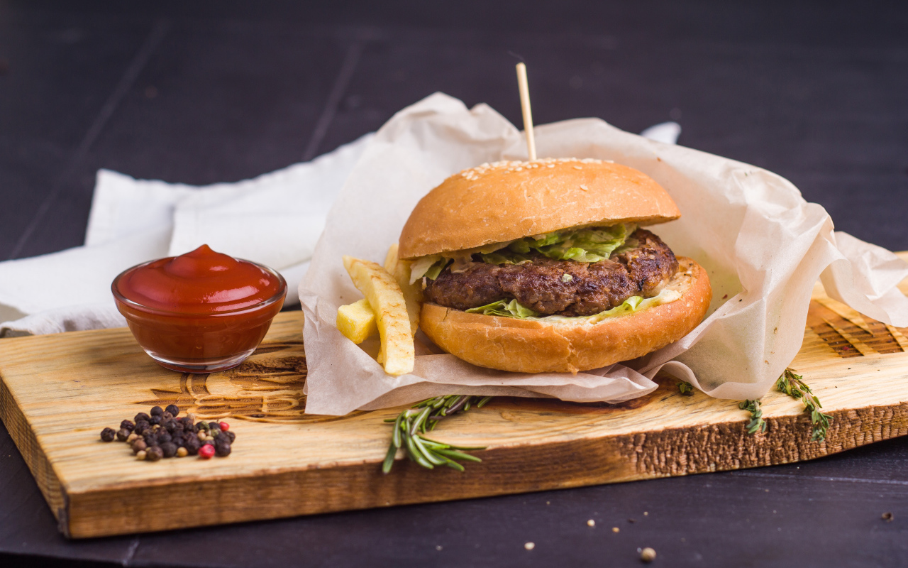 Аппетитный гамбургер с картофелем фри и кетчупом на столе