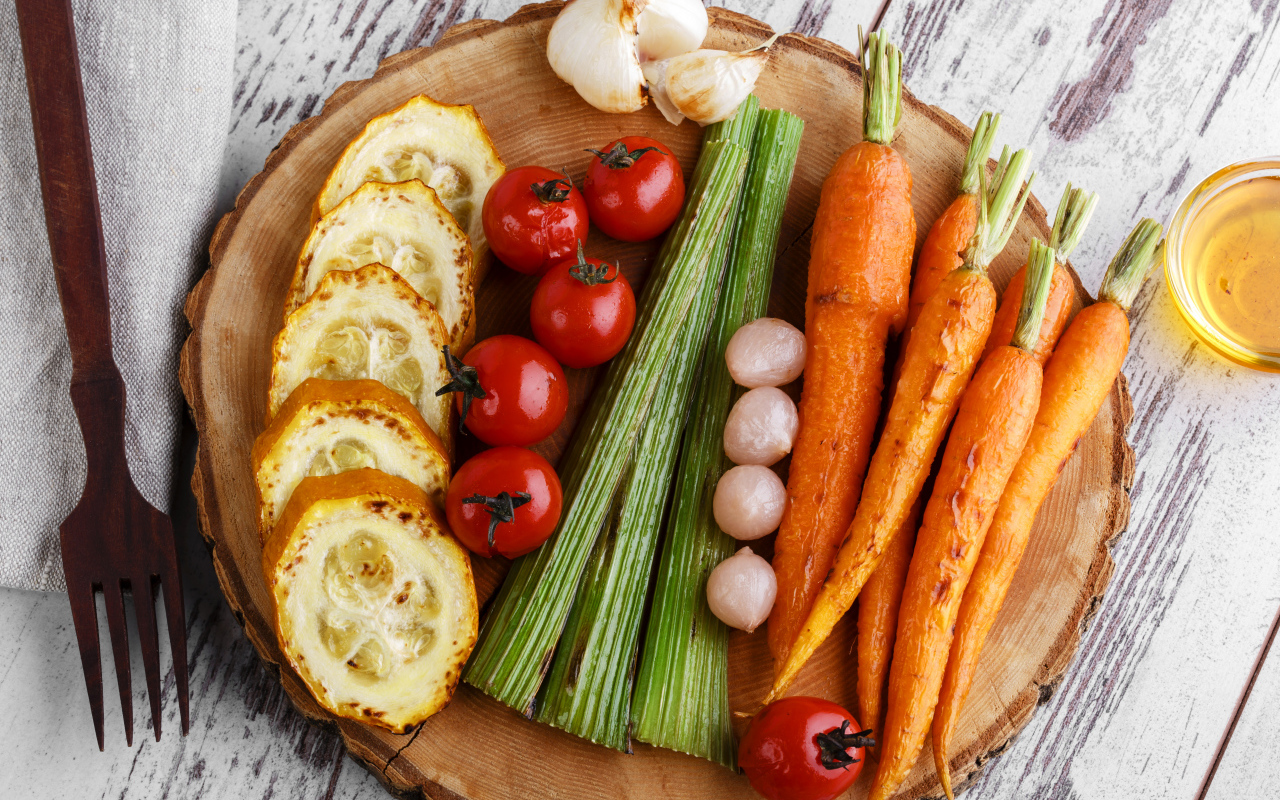 Печеные кабачки, помидоры, морковь, сельдерей и чеснок на разделочной доске