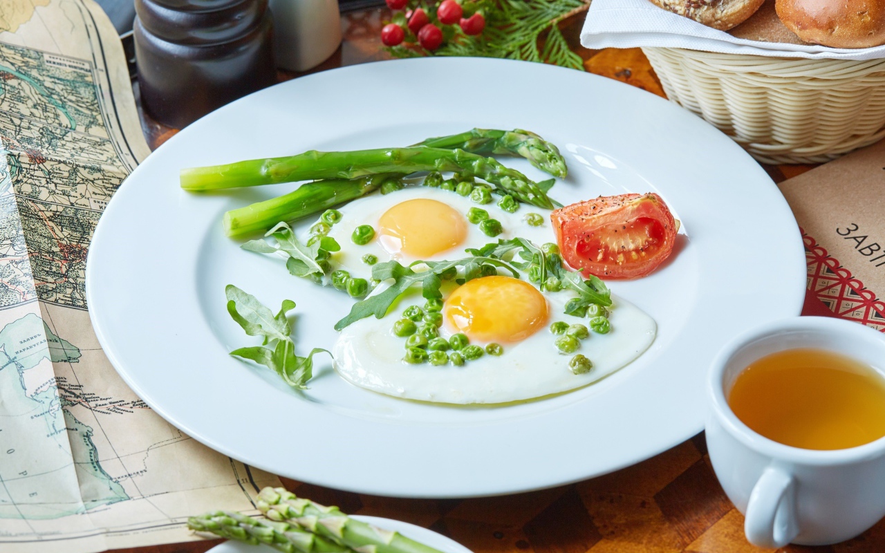 Fried eggs for breakfast with green peas and asparagus