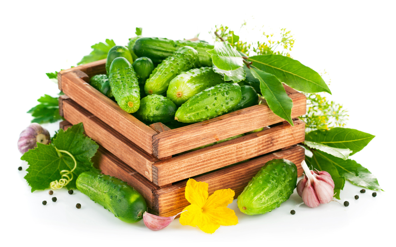 Зеленые свежие огурцы в деревянном ящике на белом фоне