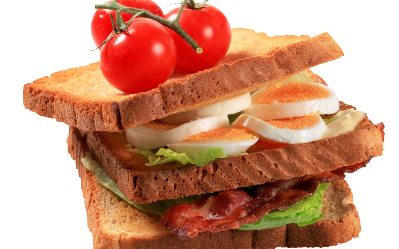 Сэндвич с яйцами, беконом и помидорами на белом фоне