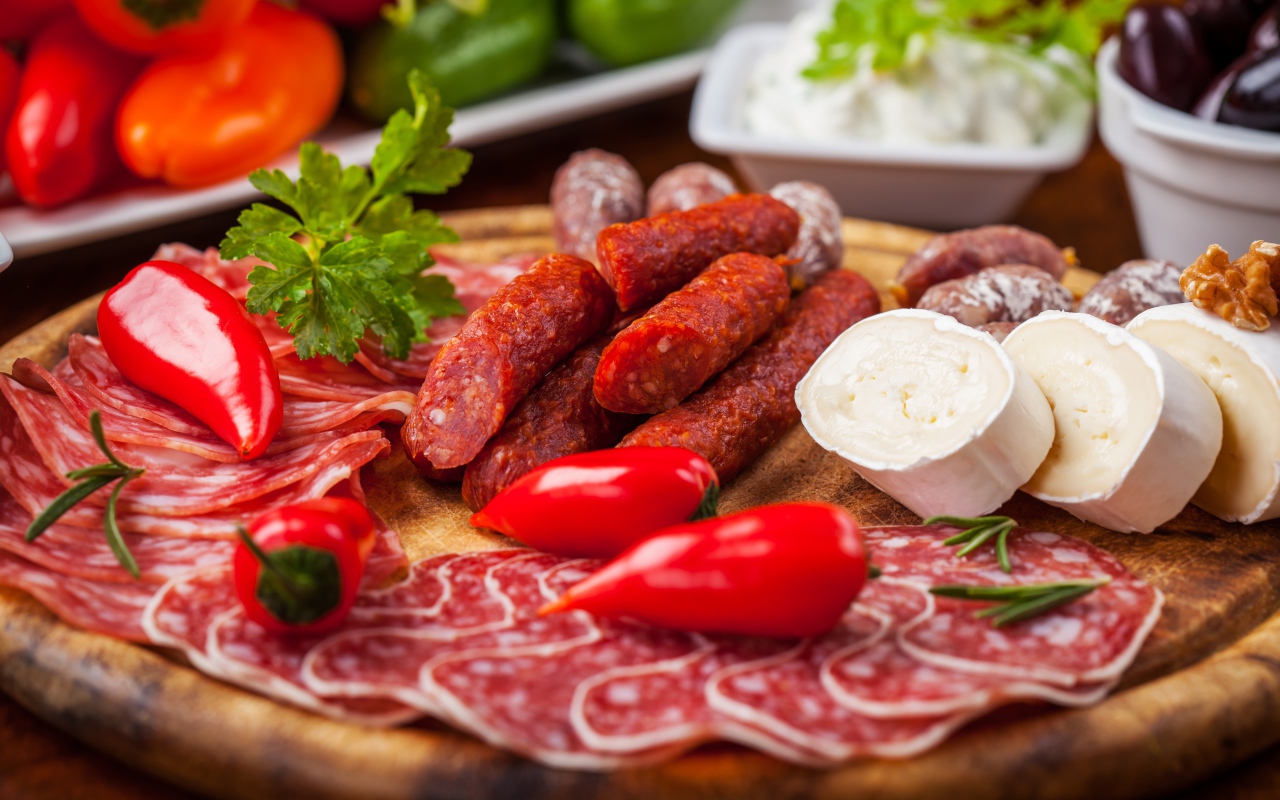 Колбаса с кусками сыра и мяса на столе с перцем