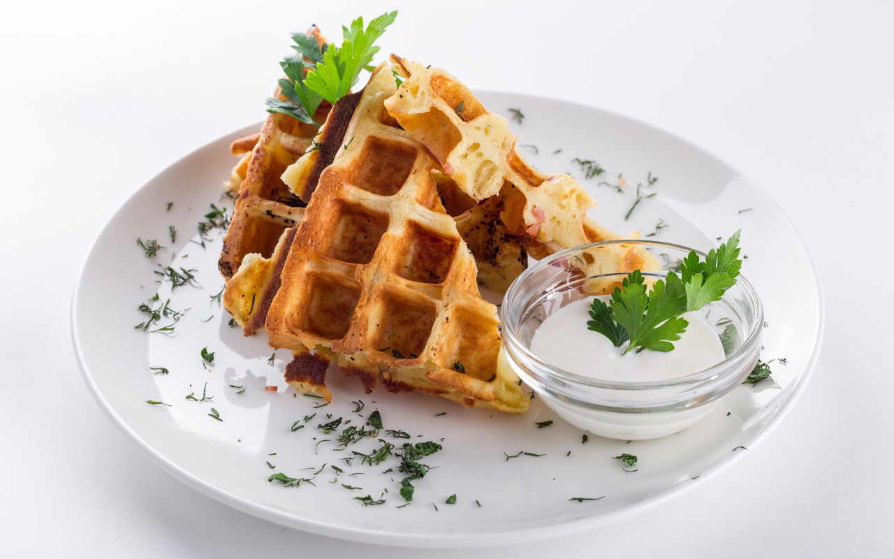 Несладкие вафли на белой тарелке с зеленью и соусом