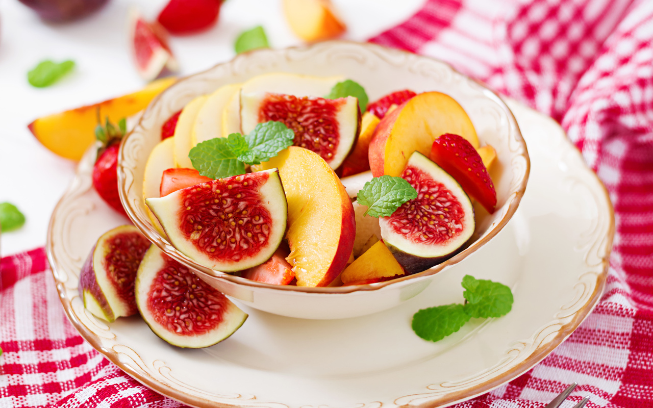 Свежие кусочки инжира и яблока в тарелке на столе