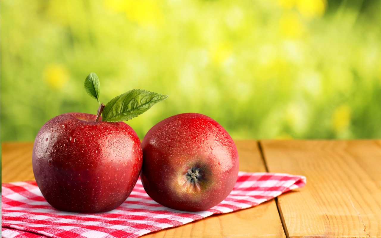 Два красных яблока в каплях воды лежат на полотенце 