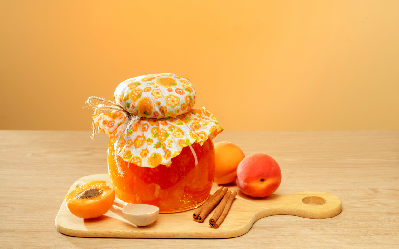 Банка абрикосового джема на столе с фруктами