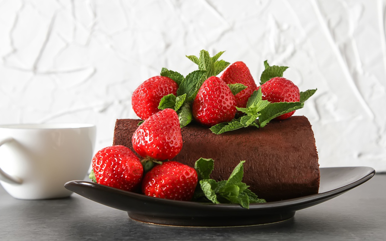 Кусок шоколадного торта со свежей клубникой на тарелке