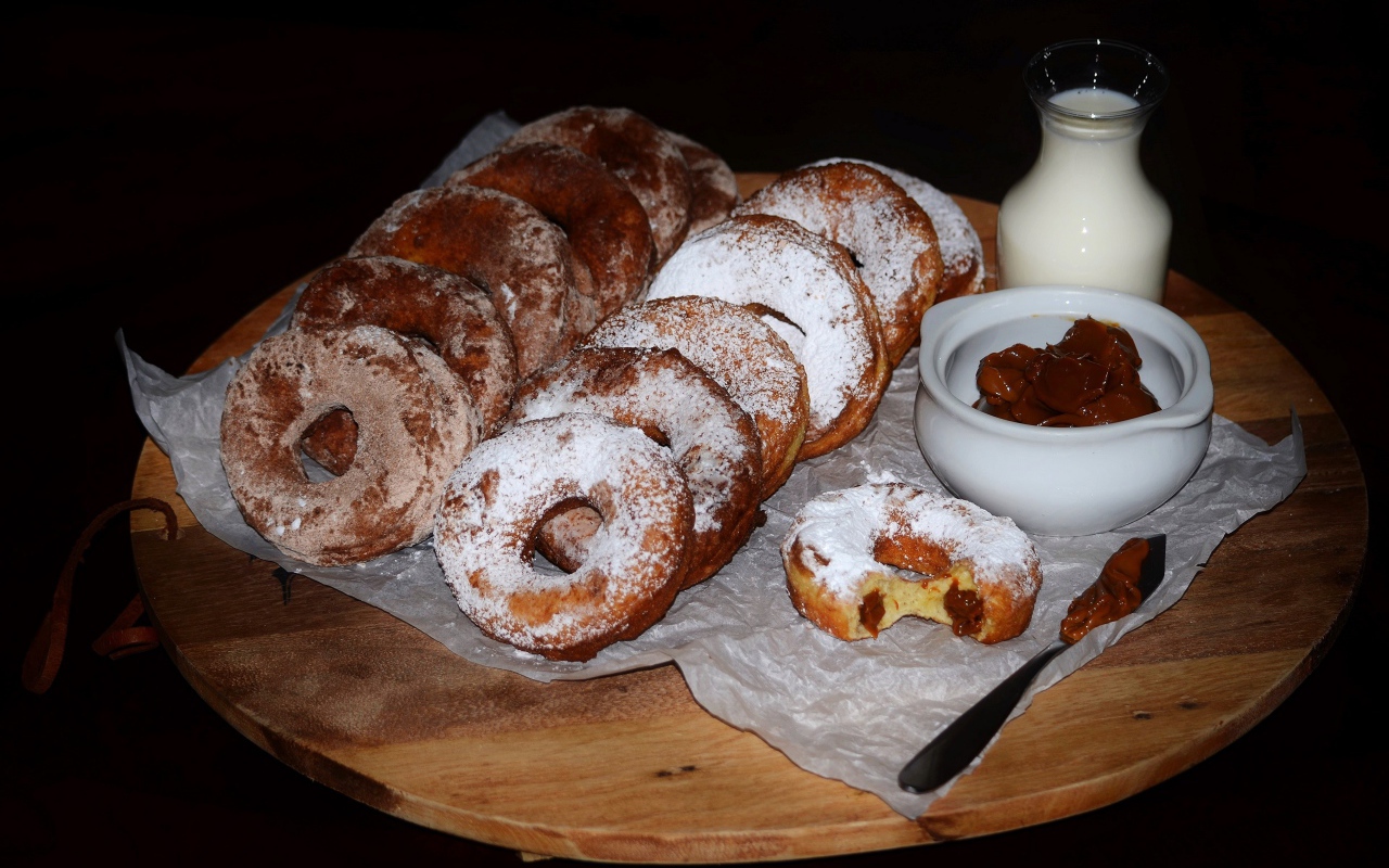 Аппетитные пончики со сгущенкой и свежим молоком на столе